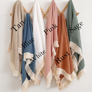 May include: Six muslin baby blankets with fringe trim in various colors: tan, blue, white, pink, rust, and sage.