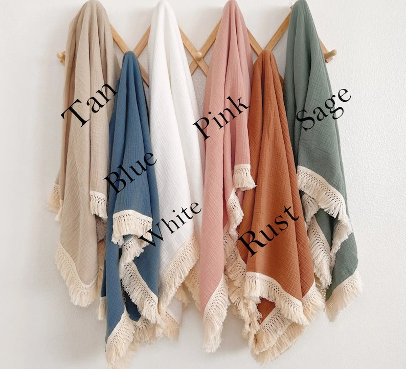 May include: Six muslin baby blankets with fringe trim in various colors: tan, blue, white, pink, rust, and sage.