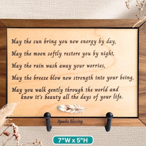May include: Wooden framed sign with a light wood background, featuring a poem and a feather illustration. The sign is 7 inches wide and 5 inches high. The text reads "May the sun bring you new energy..." and is signed "Apache Blessing."
