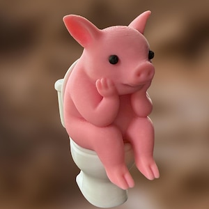 May include: A pink figurine of a pig sitting on a white toilet. The pig has black eyes and is resting its head on its hands. The background is a blurred brown and tan.
