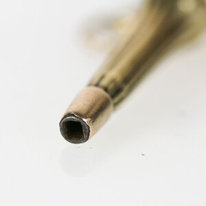 May include: Close-up of a gold-toned metal key with a square-shaped hole at the end.