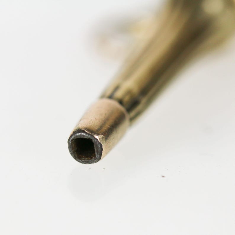 May include: Close-up of a gold-toned metal key with a square-shaped hole at the end.