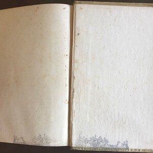 May include: An open book with blank pages. The book has a brown cover with a worn, aged appearance.