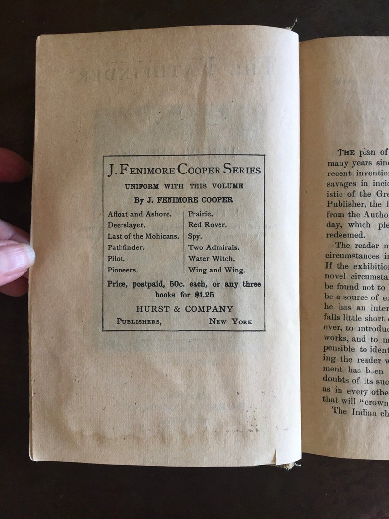 May include: A vintage book cover for the J. Fenimore Cooper Series. The cover is printed in black ink on a cream-colored paper background. The title of the series is "J. Fenimore Cooper Series" and the subtitle is "Uniform with this volume". The author's name is listed as "By J. Fenimore Cooper". The cover lists several titles by the author, including "Afloat and Ashore", "Prairie", "Deerslayer", "Red Rover", "Last of the Mohicans", "Spy", "Two Admirals", "Water Witch", "Wing and Wing", "Pilot", and "Pioneers". The cover also includes the price of the books, which is 50 cents each or $1.25 for any three books. The publisher is listed as "Hurst & Company, Publishers, New York".