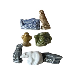 May include: A set of nine ceramic figurines depicting various animals, including a polar bear, a bird, a fish, a turtle, and a whale. The figurines are painted in various colors, including white, brown, blue, green, and gray.