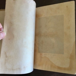 May include: An open book with a blank page on the left and a page with a rectangular space for a photo on the right. The photo space is surrounded by a thin border and has a faint watermark.