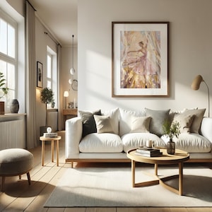 以下が含まれることがあります： ピンクのドレスを着たバレリーナの印象派の絵画が描かれた額装アートプリント。白いソファ、様々なクッション、木製のコーヒーテーブル、小さな丸いオットマンが置かれたリビングルームの壁に飾られています。