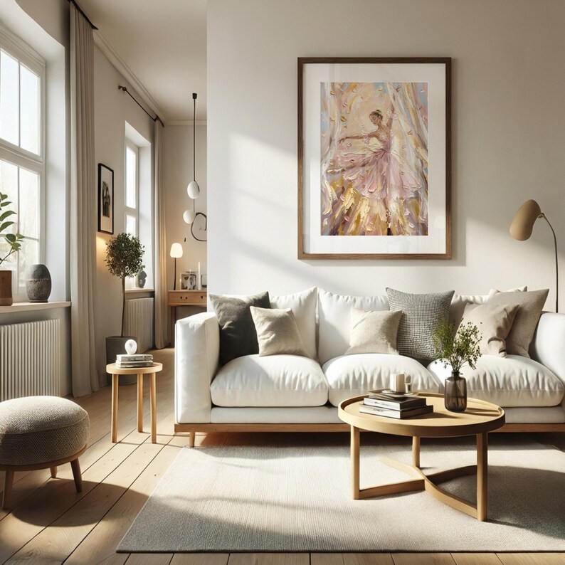 以下が含まれることがあります： ピンクのドレスを着たバレリーナの印象派の絵画が描かれた額装アートプリント。白いソファ、様々なクッション、木製のコーヒーテーブル、小さな丸いオットマンが置かれたリビングルームの壁に飾られています。