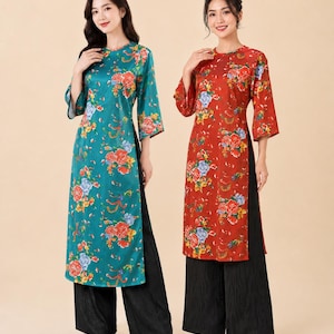 Puede incluir: Dos túnicas largas con mangas tres cuartos y aberturas laterales, una en color verde azulado y otra en rojo, ambas con un vibrante estampado floral de flores rojas, naranjas y azules. Cada túnica se combina con pantalones negros anchos y texturizados.