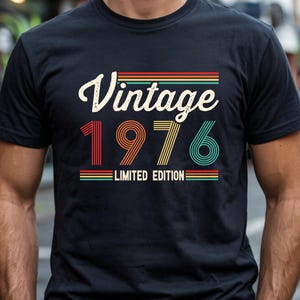 May include: Black t-shirt featuring the text "Vintage 1976 Limited Edition" in a retro style. The text is in white, red, orange, yellow, and teal. The shirt has a crew neck and short sleeves.