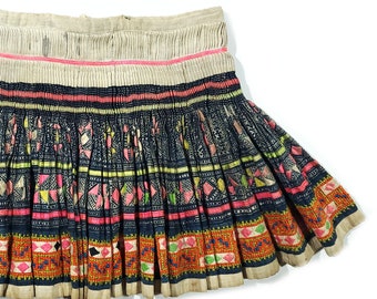 May include: A pleated skirt with a colorful geometric pattern in shades of pink, blue, green, and orange. The skirt is made of a lightweight fabric and has a simple design.