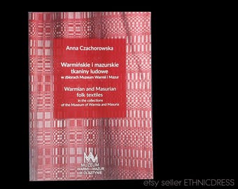 May include: A red book with a white and red patterned cover. The title is "Warmian and Masurian folk textiles in the collections of the Museum of Warmia and Masuria".