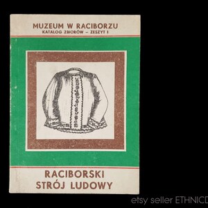 May include: A green and brown book cover with the title "Muzeum w Raciborzu" and the text "Katalog Zbiorow - Zeszyt I". The cover also features a black and white illustration of a traditional Polish folk costume.