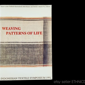 May include: Book cover with a woven fabric pattern in shades of brown, black, white, and red. The title is "Weaving Patterns of Life" and the subtitle is "Indonesian Textile Symposium 1991".
