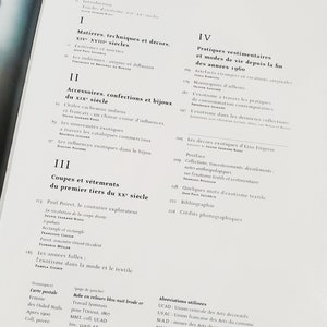 Może przedstawiać: Okładka książki z tytułem "Ethnic Dress: Touches of Exotism, XIV-XX Centuries". Okładka książki jest podzielona na cztery sekcje, każda z numerem rzymskim i tytułem. Książka opowiada o historii odzieży i mody etnicznej.