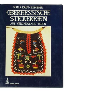 May include: A book cover with the title "Oberhessische Stickereien Aus Vergangenen Tagen" by Gisela Kraft-Schneider. The cover features a colourful embroidered design on a black background.