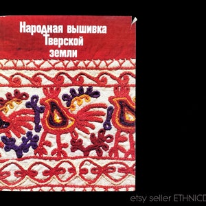 May include: A vintage book cover with the title "Народная вышивка Тверской земли" in red lettering. The cover features a colorful embroidered design of birds and floral patterns on a white background.