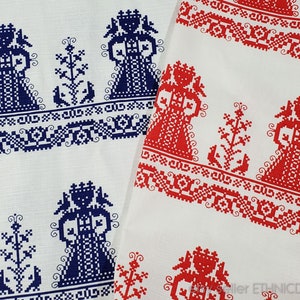 Op de afbeelding: Witte stof met een herhalend patroon van blauwe en rode gestileerde figuren. De figuren worden omringd door geometrische ontwerpen. De stof is waarschijnlijk bedoeld voor gebruik in kleding of huisdecoratie.