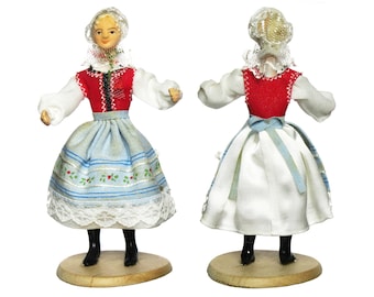 Peut inclure: Une poupée en bois vêtue d'un costume folklorique traditionnel. La poupée porte une blouse blanche, un gilet rouge, une jupe bleu et blanc et un couvre-chef en dentelle blanche. La poupée est debout sur une base en bois.