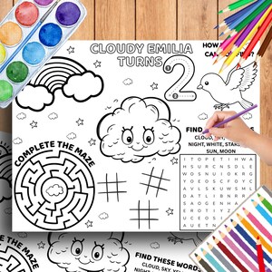 以下が含まれることがあります： 「Cloudy Emilia Turns 2」の文字が入った白黒のアクティビティプレースマット。プレースマットには、迷路、単語検索、雲、虹、鳥のイラストが描かれています。水彩絵の具セットと色鉛筆が見えます。