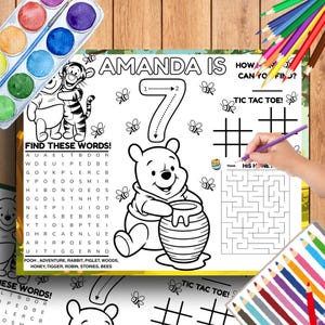 May include: A children's activity placemat featuring Winnie the Pooh, bees, and the text "Amanda is 7". The placemat includes a word search, tic-tac-toe, and a maze. The design is suitable for a 7-year-old's birthday.