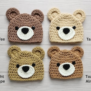 May include: Four crocheted bear hats in coffee, tan, light taupe, and toasted almond colors. Each hat features two rounded ears, a white muzzle, a black nose, and two black eyes. The text labels Coffee, Tan, Light Taupe, and Toasted Almond are visible.