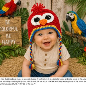 Puede incluir: Un beb&eacute; sonriente con un gorro de b&uacute;ho de ganchillo rojo, amarillo, azul y blanco. El gorro tiene orejeras trenzadas. El fondo incluye un letrero que dice "BE COLORFUL BE HAPPY" y dos figuras de loro.
