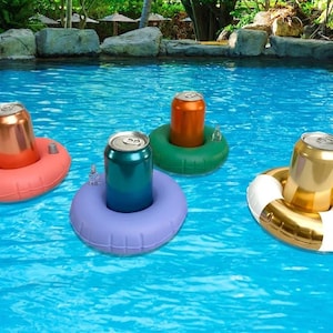 Può includere: Quattro porta bevande gonfiabili colorati galleggiano in una piscina. Ogni porta bevande ha un colore diverso: rosso, verde, viola e oro. Ogni porta bevande contiene una lattina di bevanda. L'acqua della piscina è blu brillante.