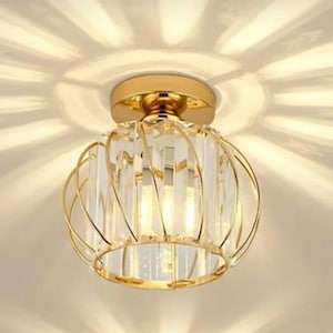 Puede incluir: Tres luces de techo doradas con un diseño de cristal y vidrio. Las luces son redondas con una estructura similar a una jaula y proyectan un patrón de estrella en el techo. Las luces están montadas en un techo blanco.