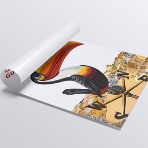 以下が含まれることがあります： カラフルなオオハシのイラストが描かれた丸められたポスター。オオハシは、オレンジと赤の大きな嘴と、黒、白、黄色の羽を持っています。ポスターは部分的に広げられており、詳細な都市景観が示されています。