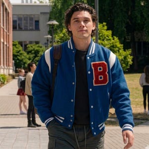 May include: A blue varsity jacket with white sleeves and a large red letter B patch on the chest. The jacket features a snap-button front closure, white and blue striped ribbed cuffs, and a matching striped collar, worn over a black shirt.