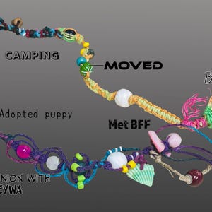 May include: A handmade macrame bracelet with colorful beads, shells, and the text "Camping", "Adopted puppy", "Moved", "Met BFF", "Birth", and "Communion with EYWA". The bracelet features a variety of colors and textures.