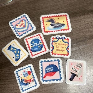 Könnte beinhalten: Eine Sammlung von Aufklebern im Poststempel-Design. Designs umfassen eine Eistaucher, ein Hockey-Trikot, eine Socke, eine Baseballkappe, ein Mikrofon und die Sätze "Lovers", "I'm coming to the cottage" und "It's a lie, told you that".