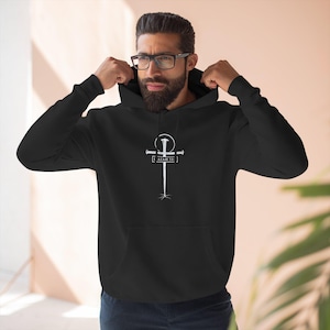 May include: Black hoodie with a white cross design. The cross features a nail-like shape and the text "ISAIAH 53" below the crossbar. The hoodie has a drawstring hood and long sleeves. The design is centered on the chest.