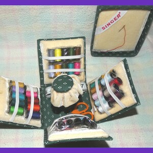 May include: A green fabric sewing kit with compartments for thread spools, needles, and a pincushion. The kit is open to reveal the contents, including a small pair of scissors and a tape measure. The kit has the word "SINGER" printed on the top.
