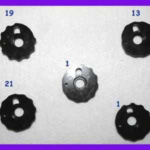 May include: Five black plastic sewing machine presser feet with different numbers printed on them: 1, 13, 19, 21.