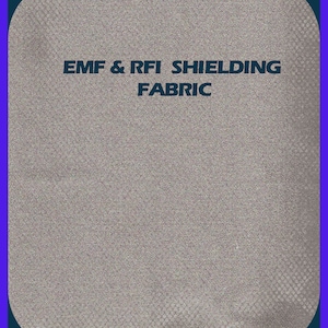 May include: A close-up of a gray fabric with a textured pattern. The fabric is labeled "EMF & RFI SHIELDING FABRIC". A yellow ruler is at the bottom of the image.