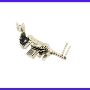 May include: A silver sewing machine foot with a needle guide and a SINGER brand label. The foot has a lever that can be adjusted to change the width of the stitch.