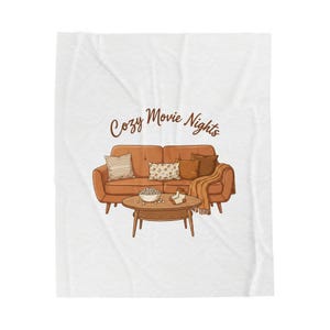 May include: A throw blanket with a cozy movie night theme. The illustration features a brown sofa with pillows, a coffee table with popcorn and a blanket. The words "Cozy Movie Nights" are written in brown script.