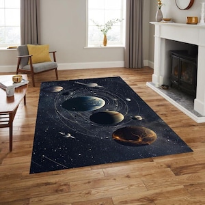 Op de afbeelding: Een rechthoekig vloerkleed met een kosmisch ontwerp met planeten, sterren en orbitale paden tegen een donkerblauwe achtergrond. Het vloerkleed ligt op een houten vloer in een woonkamer.