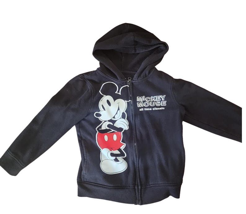 May include: Black zip-up hoodie featuring a large graphic of Mickey Mouse in white, red, and black. The hoodie has a hood and the text "Mickey Mouse all time classic" on the right side. The hoodie is made of a soft material.