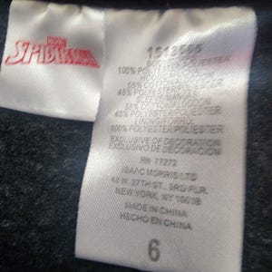 Puede incluir: Una etiqueta de ropa blanca con el logotipo de Marvel Spider-Man en rojo. La etiqueta incluye informaci&oacute;n sobre la composici&oacute;n de la tela, incluyendo poli&eacute;ster y algod&oacute;n, y la talla, que es un 6. La etiqueta tambi&eacute;n incluye la informaci&oacute;n del fabricante.