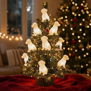 May include: A small artificial green Christmas tree decorated with multiple white, glowing dog-shaped ornaments and thin string lights. The tree features a sturdy, textured brown wooden base and is adorned with small, round, dark green ornaments.