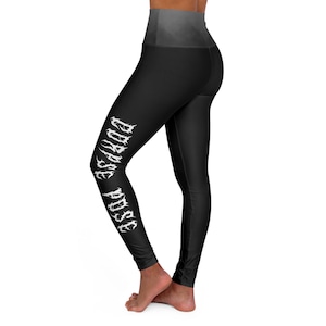 Può includere: Leggings neri con vita alta e la scritta bianca "CORPSE POSE" stampata verticalmente sulla gamba sinistra. I leggings hanno un effetto sfumato nella parte superiore, che passa dal nero al grigio.