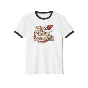 A white t-shirt with a black border and a graphic design featuring the text "Not Today, Retrograde" along with a planet and stars.
