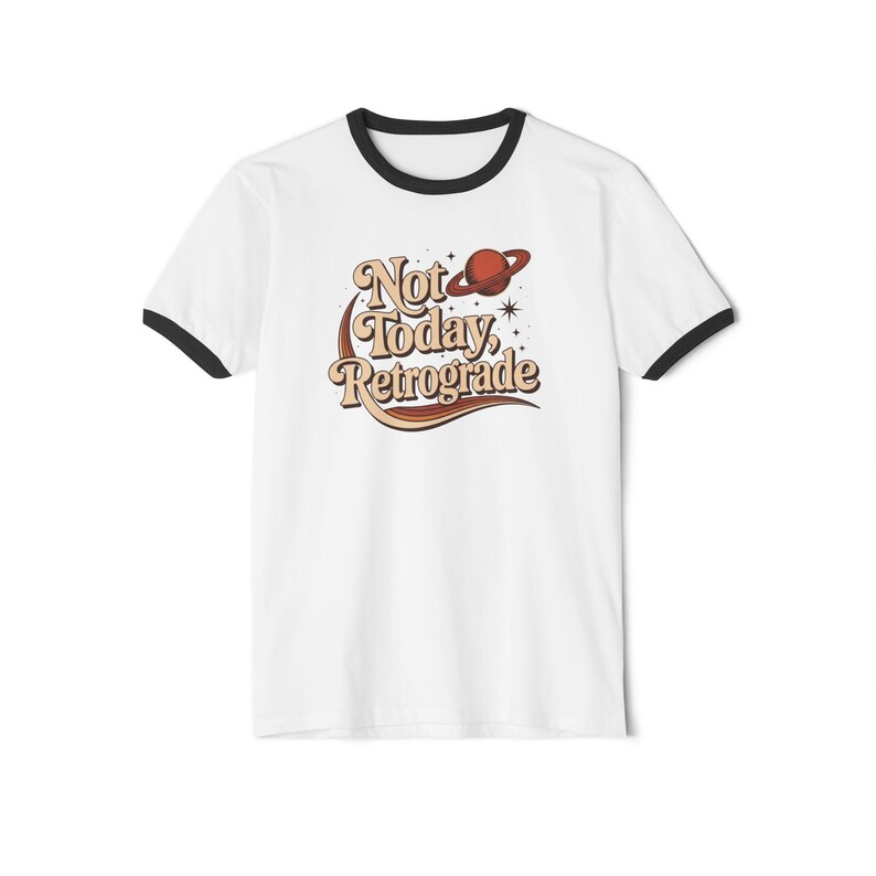 A white t-shirt with a black border and a graphic design featuring the text "Not Today, Retrograde" along with a planet and stars.