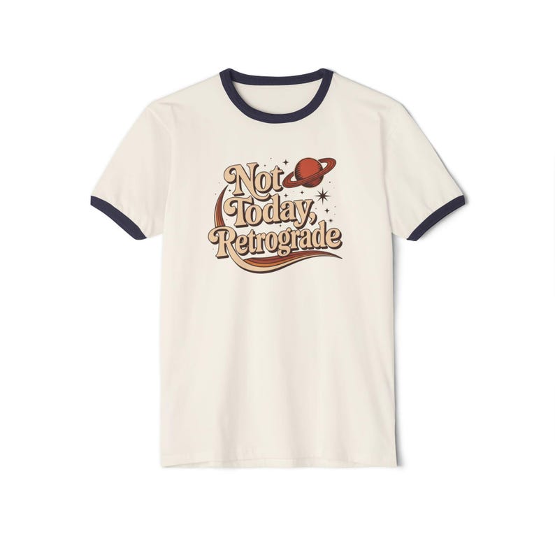 A white t-shirt with a graphic design featuring a planet and the text "Not Today, Retrograde" printed on it.