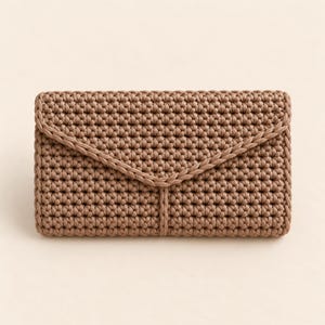 Peut inclure: Une pochette rectangulaire de style enveloppe fabriquée à partir d'un cordon ou d'un fil marron moka uni, avec un motif de points au crochet dense et uniforme. Le rabat présente un détail de bordure tressée le long de la fermeture triangulaire.