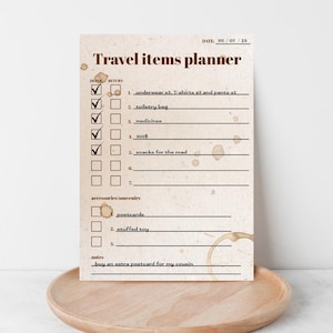Könnte beinhalten: Ein Reiseplaner im Vintage-Stil mit einer Checkliste für Reiseutensilien, darunter Unterwäsche, Toilettenartikel und Snacks. Der Planer liegt auf einem Holztablett.