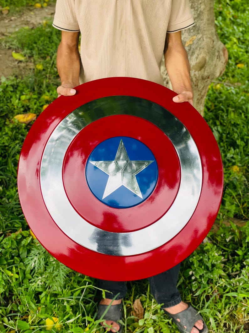 May include: A red, white, and blue shield with a star in the center. The shield is round with a silver band and a blue circle in the middle. The outer ring is red.